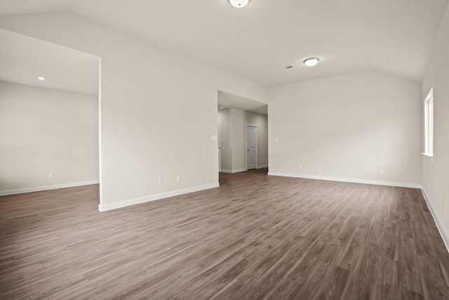 empty room featuring vaulted ceiling and dark wood-type flooring