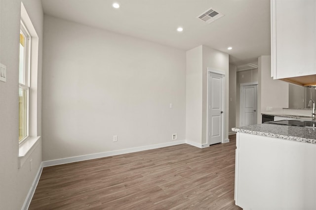 kitchen with hardwood / wood-style flooring, light stone countertops, and white cabinets