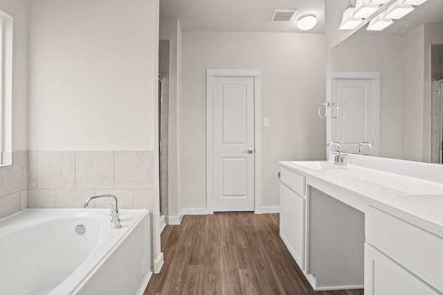 bathroom featuring wood-type flooring, plus walk in shower, and vanity