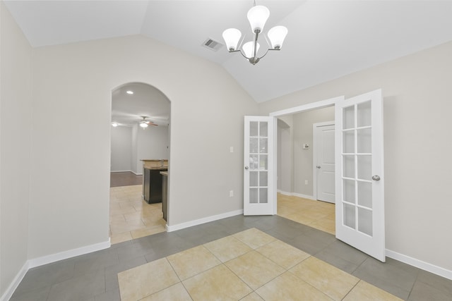 tiled spare room featuring vaulted ceiling, ceiling fan with notable chandelier, and french doors