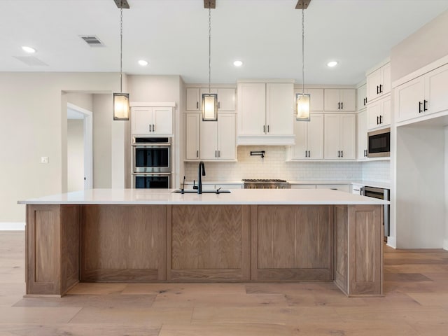 kitchen with light hardwood / wood-style flooring, a large island, appliances with stainless steel finishes, and decorative light fixtures