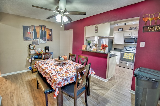 dining room featuring light wood-type flooring, ceiling fan, and a textured ceiling