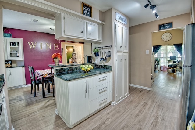 kitchen with ceiling fan, white cabinets, track lighting, dark stone countertops, and light hardwood / wood-style floors