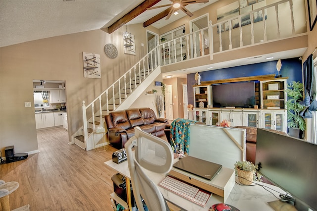 interior space with light hardwood / wood-style floors, ceiling fan, beamed ceiling, and high vaulted ceiling