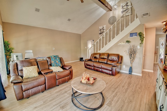 living room featuring a textured ceiling, light hardwood / wood-style flooring, and lofted ceiling