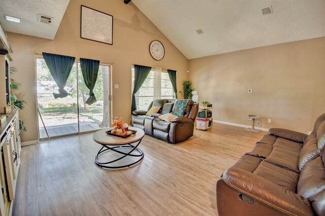 living room with light hardwood / wood-style flooring, a textured ceiling, and high vaulted ceiling