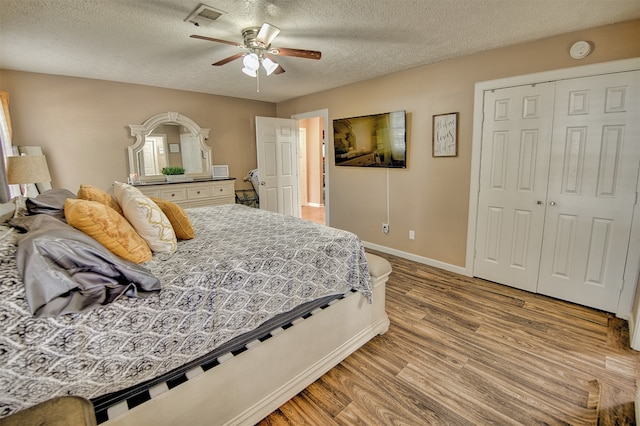 bedroom featuring ceiling fan, a textured ceiling, light hardwood / wood-style flooring, and a closet