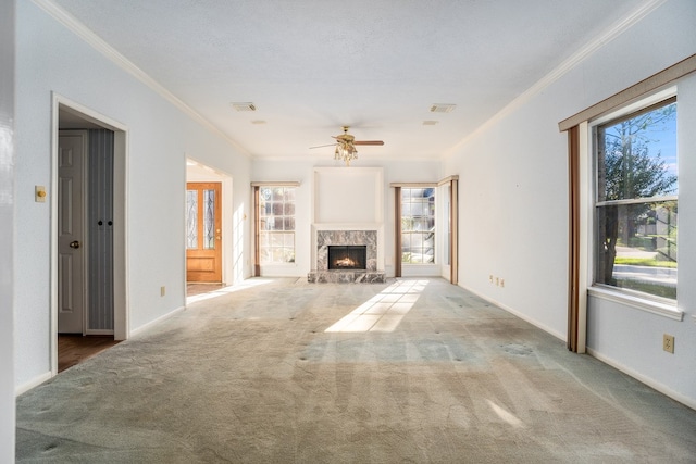 unfurnished living room featuring light carpet, ceiling fan, crown molding, and a premium fireplace