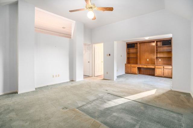 unfurnished living room with light carpet, built in desk, ceiling fan, and lofted ceiling