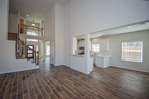 unfurnished living room with dark wood-type flooring, sink, and a high ceiling