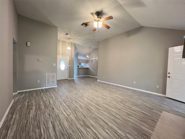 unfurnished living room with lofted ceiling, hardwood / wood-style floors, and ceiling fan with notable chandelier