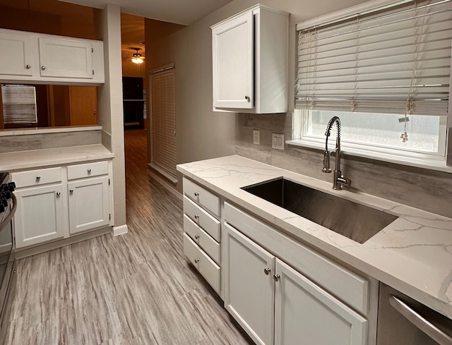 kitchen featuring light hardwood / wood-style flooring, light stone counters, white cabinetry, and sink