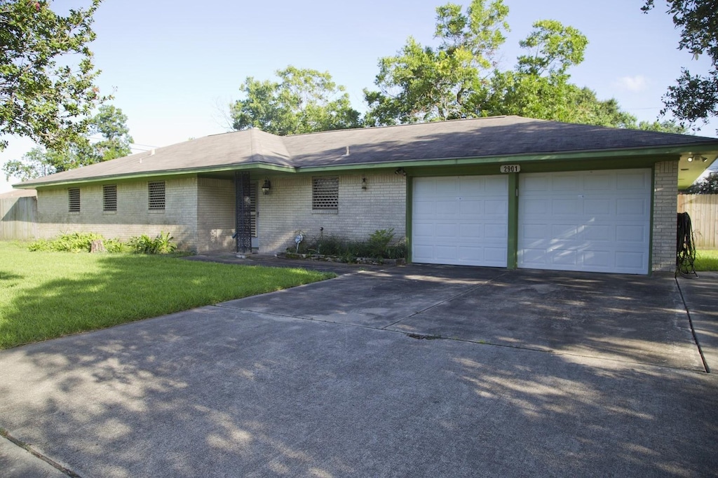 ranch-style house featuring a front yard, an attached garage, brick siding, and concrete driveway