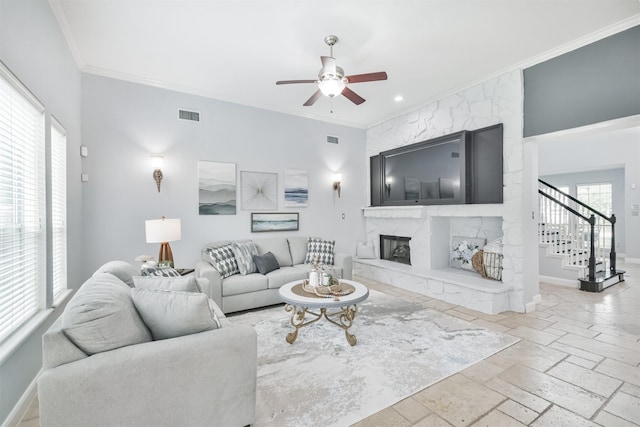 living room featuring ceiling fan, ornamental molding, and a fireplace