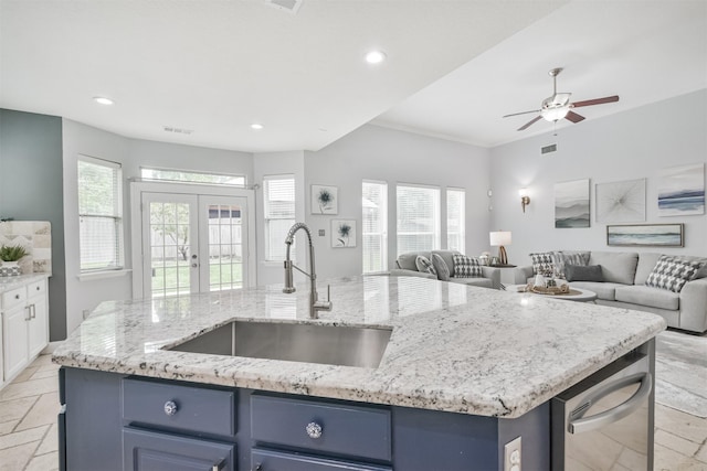 kitchen featuring white cabinets, french doors, sink, a kitchen island with sink, and blue cabinets