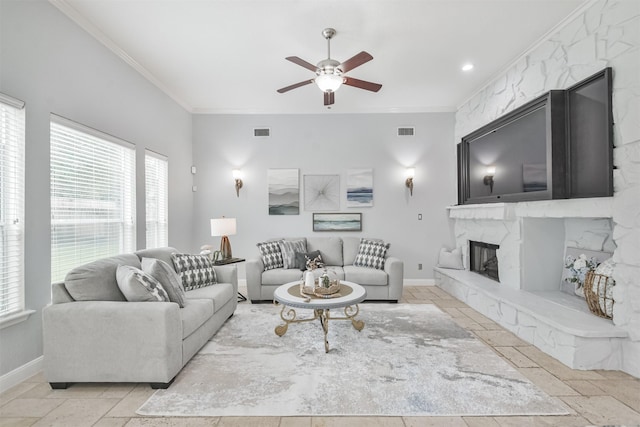 living room featuring ceiling fan, a stone fireplace, and ornamental molding