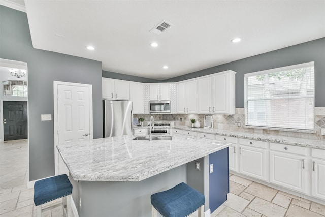 kitchen featuring appliances with stainless steel finishes, tasteful backsplash, a breakfast bar area, and an island with sink