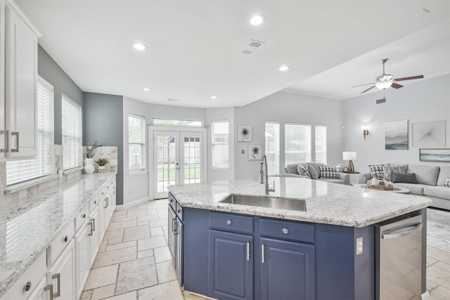 kitchen with a center island with sink, sink, blue cabinetry, white cabinets, and french doors