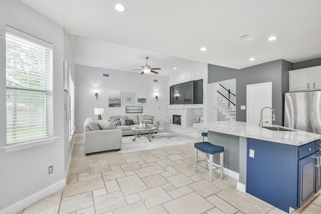 kitchen featuring a breakfast bar area, blue cabinetry, a kitchen island with sink, white cabinets, and sink