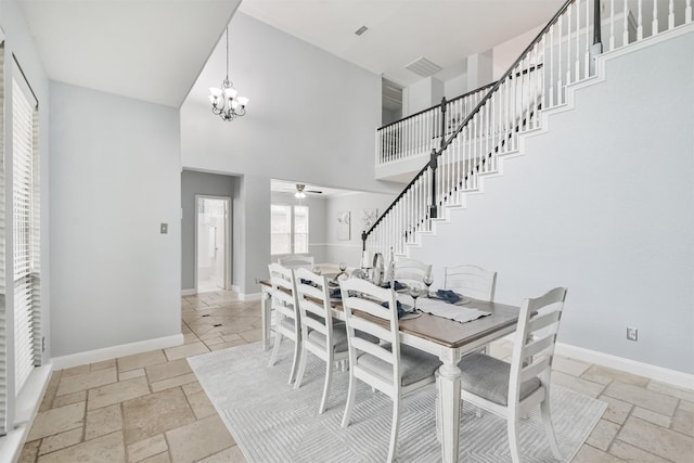 dining space with ceiling fan with notable chandelier and a towering ceiling