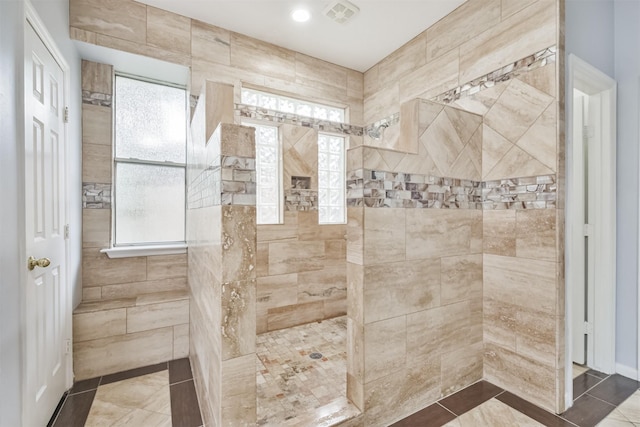 bathroom featuring plenty of natural light, tile patterned floors, and a tile shower