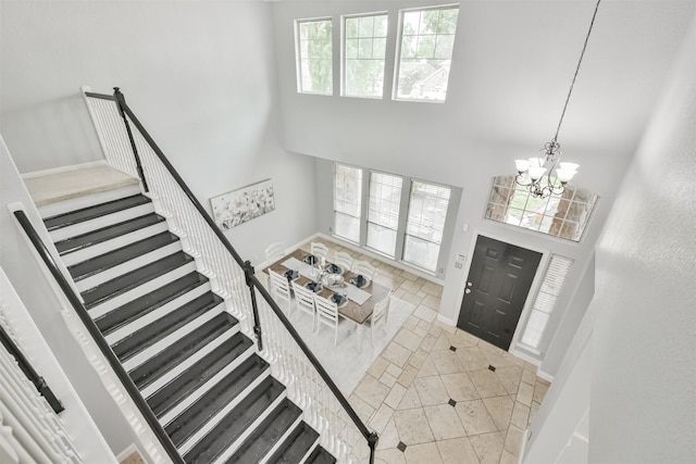 foyer entrance with a high ceiling, light tile patterned floors, and a notable chandelier