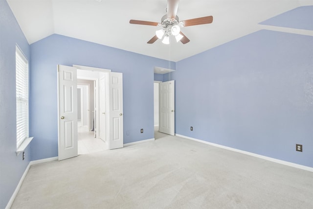 unfurnished bedroom with ceiling fan, light colored carpet, vaulted ceiling, and ensuite bathroom