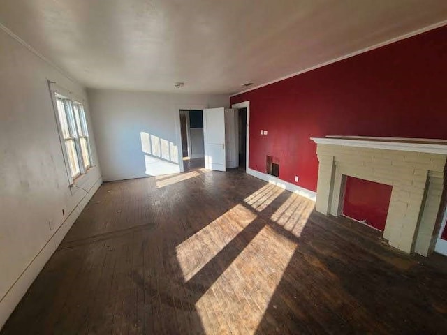 unfurnished living room featuring dark hardwood / wood-style floors and a brick fireplace