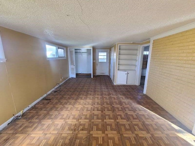 hallway featuring a textured ceiling, brick wall, and dark parquet flooring