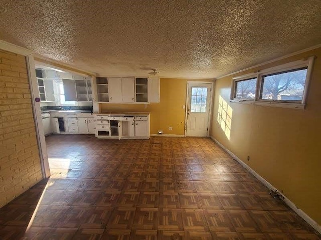 interior space featuring a textured ceiling, dark parquet flooring, and white cabinets