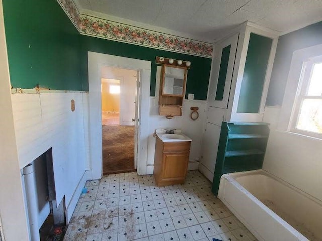 bathroom with a tub to relax in, vanity, and a textured ceiling