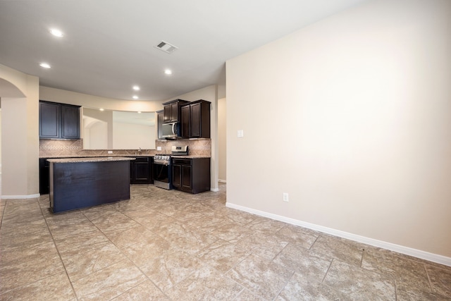 kitchen with kitchen peninsula, appliances with stainless steel finishes, dark brown cabinets, and tasteful backsplash