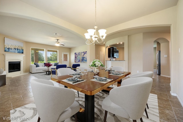 dining space with ceiling fan with notable chandelier and light tile patterned flooring