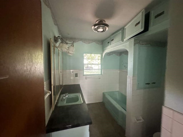 bathroom featuring tile walls, sink, and a tub