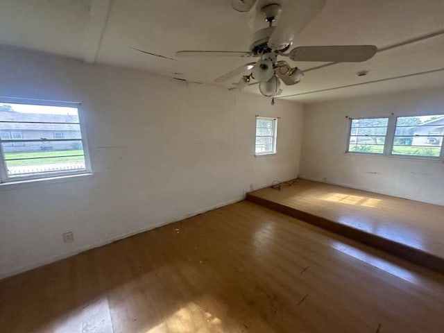 unfurnished room with a healthy amount of sunlight, hardwood / wood-style floors, and ceiling fan