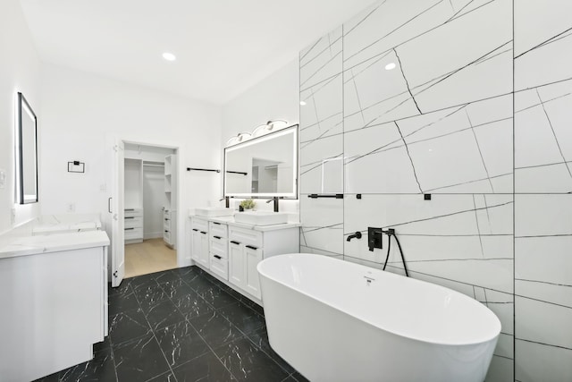 bathroom with vanity, tile walls, and a bathtub