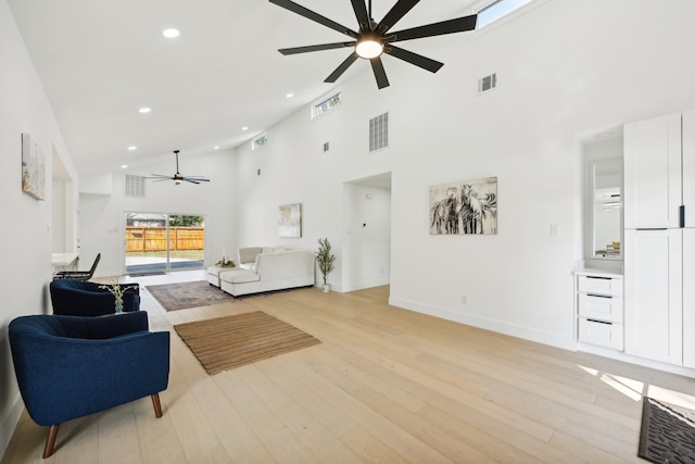 living room with light wood-type flooring, ceiling fan, and high vaulted ceiling