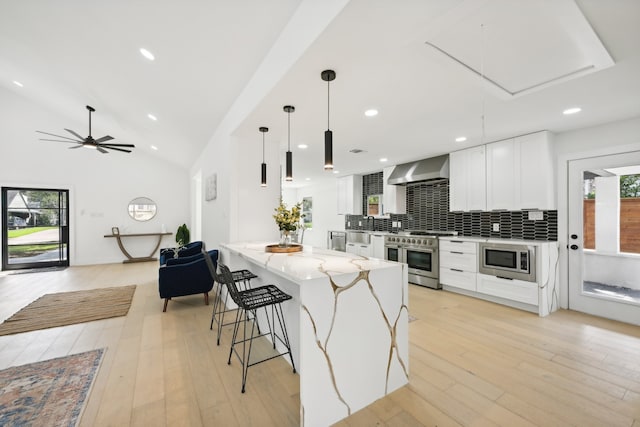 kitchen featuring light wood-type flooring, white cabinetry, decorative light fixtures, stainless steel appliances, and light stone countertops