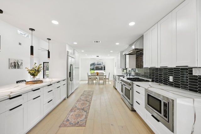 kitchen with white cabinetry, light stone countertops, high quality appliances, and hanging light fixtures