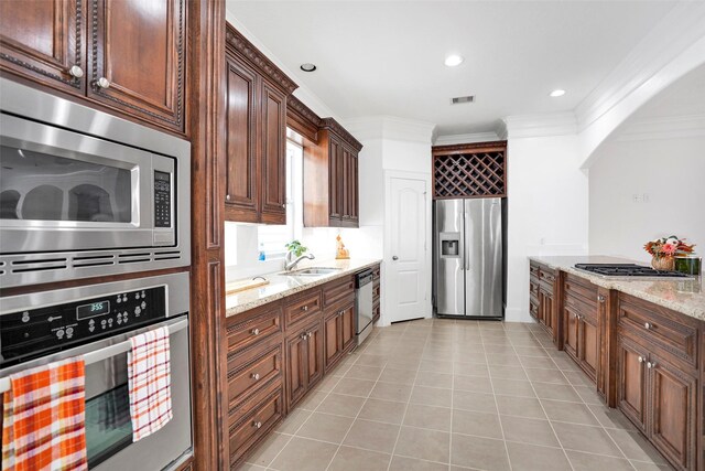 kitchen featuring appliances with stainless steel finishes, light stone counters, sink, and light tile patterned flooring