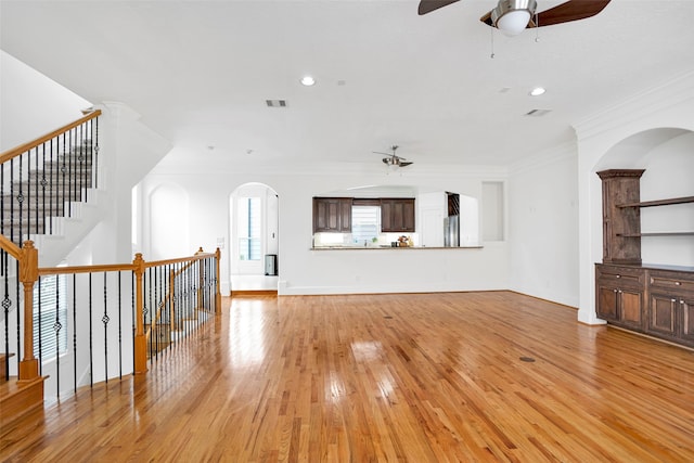 unfurnished living room with light wood-type flooring, ornamental molding, and ceiling fan