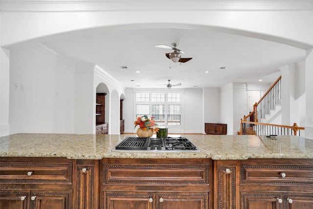 kitchen with ceiling fan, light stone countertops, ornamental molding, and stainless steel gas stovetop