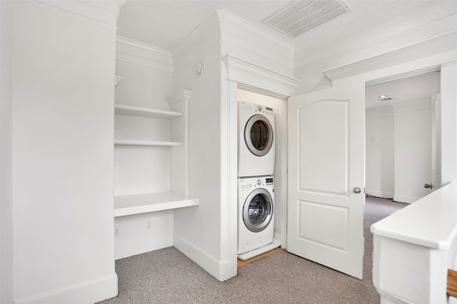 clothes washing area with crown molding, stacked washer and dryer, and carpet