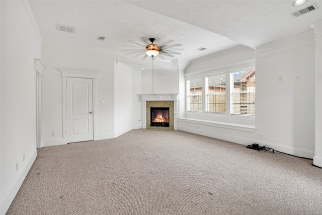 unfurnished living room featuring ornamental molding, light colored carpet, a tiled fireplace, and a textured ceiling