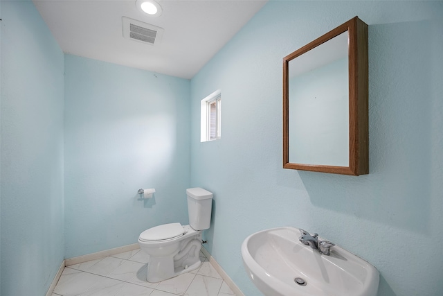 bathroom featuring toilet, sink, and tile patterned floors