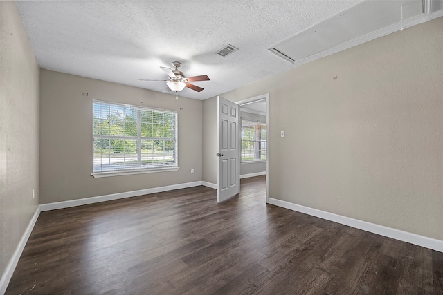 empty room with a textured ceiling, ceiling fan, and dark hardwood / wood-style flooring