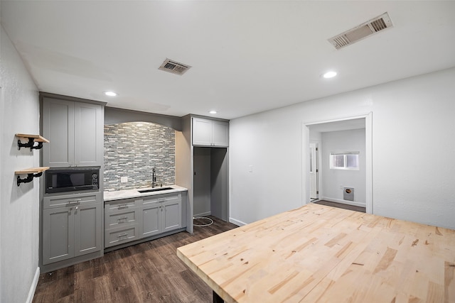 kitchen with black microwave, dark wood-type flooring, sink, and gray cabinets