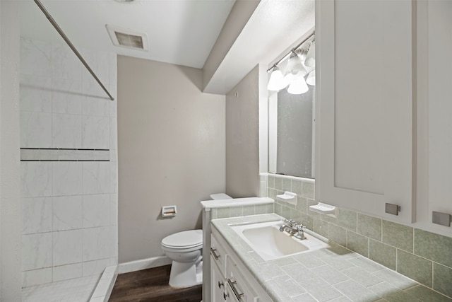 bathroom with hardwood / wood-style floors, walk in shower, toilet, tasteful backsplash, and vanity