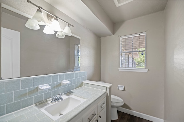 bathroom with toilet, hardwood / wood-style floors, vanity, a textured ceiling, and backsplash