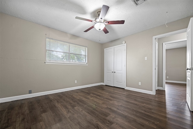 unfurnished bedroom featuring a closet, a textured ceiling, ceiling fan, and dark hardwood / wood-style floors